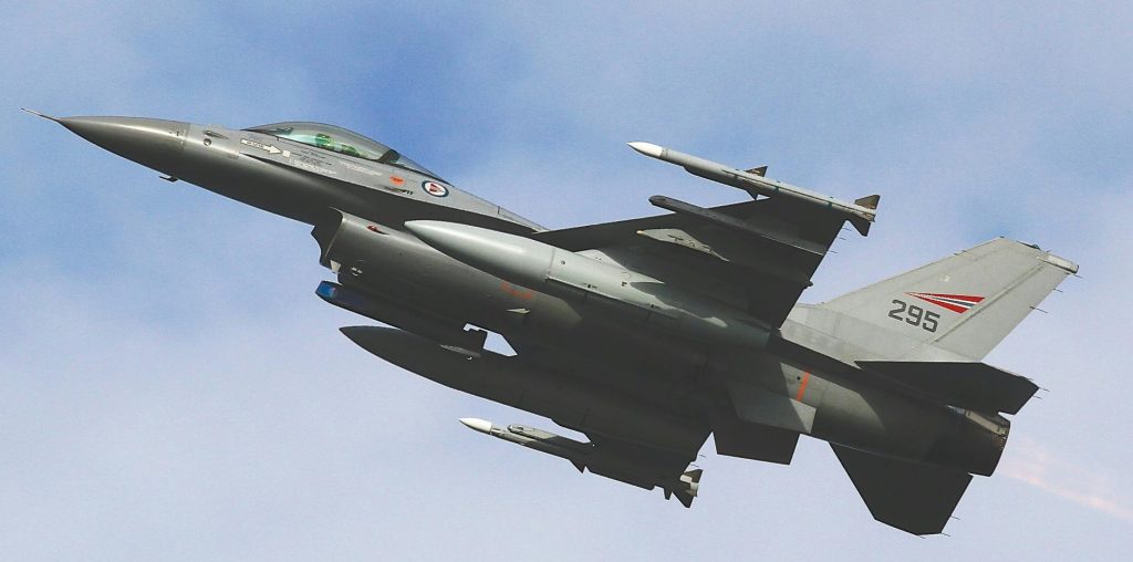 A dynamic shot of an F-16 military jet soaring through a clear sky, showcasing advanced aviation technology.